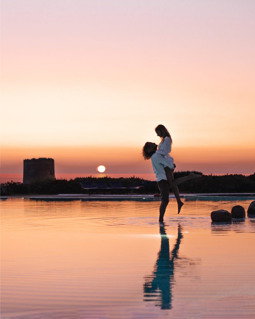 In questa immagine una coppia che si abbraccia con alle spalle un tramonto.