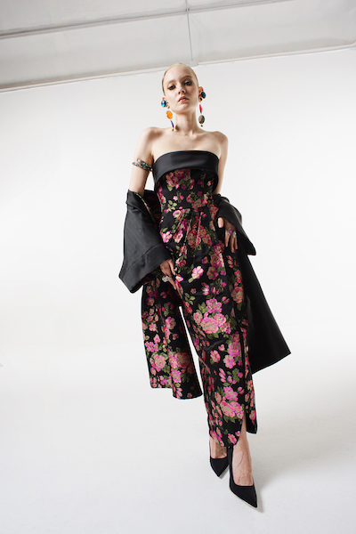 In questa foto una modella indossa un abito da cerimonia donna 2023 con stampa floreale all over. Sulle spalle una stola-cappotto nello stesso tessuto e fantasia del vestito