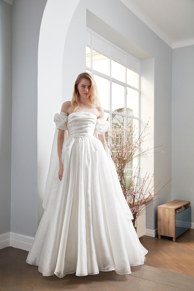 In questa foto una modella indossa un abito da sposa Peter Langner 2024: le maniche sono a sbuffo e la silhouette è scivolata ad A. Il corpetto con scollatura retta