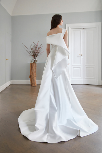 In questa foto, una modella di spalle mostra la coda architettonica dell'abito da sposa in mikado di seta della linea Peter Langner Milano 2024