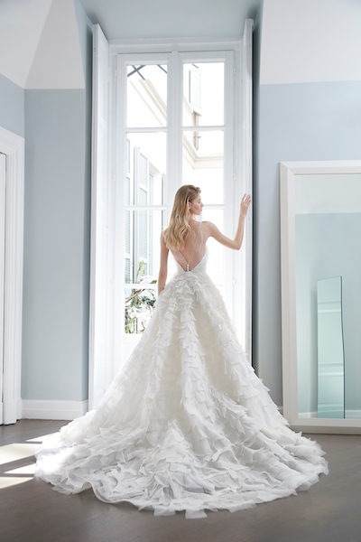 In questa foto una modella posa di spalle, mostrando il retro dell'abito da sposa con micro balze firmato Peter Langner Milano 2024 