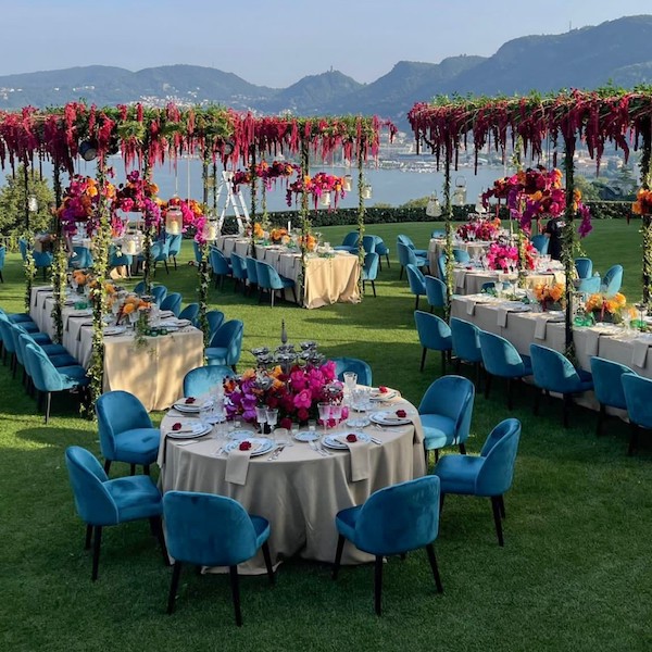 In questa immagine un allestimento da sogno con decorazioni floreali sospese, sedie in velluto blu e tanti allestimenti floreali. 