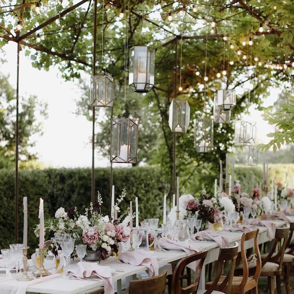 In questa immagine un allestimento per location matrimonio con candele sospese e centrotavola floreali. 