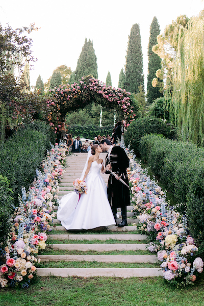 In questa immagine un allestimento per location da matrimonio da sogno con un arco di fiori e tantissimi fiori ai lati. 