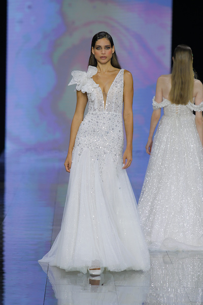 In questa foto una modella sfila sulla passerella della BBFW 2023 indossando un abito da sposa semi sirena di Nicole Milano 2024, brand del gruppo Pronovias