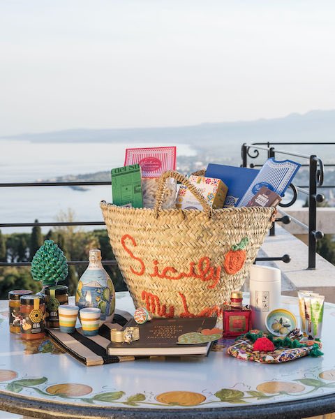 In questa foto una coffa siciliana su un tavolo, con dentro e accanto tutta una serie di prodotti tipici dell'isola