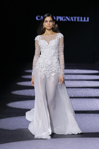 In questa foto una modella sulla passerella della Barcelona Bridal Fashion Week mentre indossa un abito da sposa Carlo Pignatelli 2024