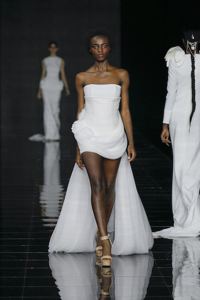 In questa foto una modella sfila sulla passerella della BBFW 2023 mentre indossa un abito da sposa corto 2024 di YolanCris
