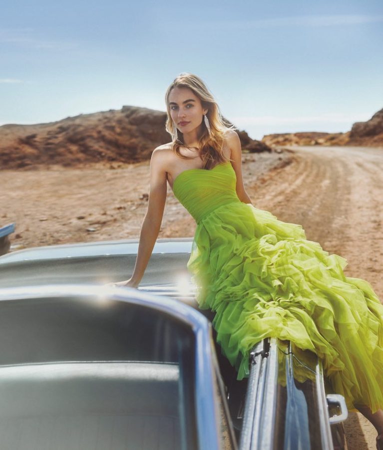 In questa foto una modella seduta su un'auto vintage decappottabile indossa un abito lungo da damigella Atelier Emé in tulle di colore verde lime
