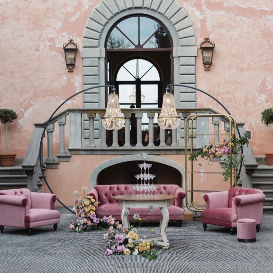 In questa immagine un allestimento per location matrimonio con divanetti rosa in velluto, maxi chandelier e dettagli floreali. 