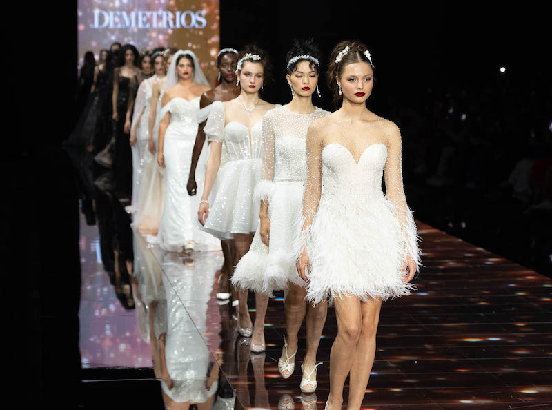 In questa foto alcune modelle sfilano sulla passerella della Barcelona Bridal Fashion Week indossando abiti da sposa Demetrios 2024