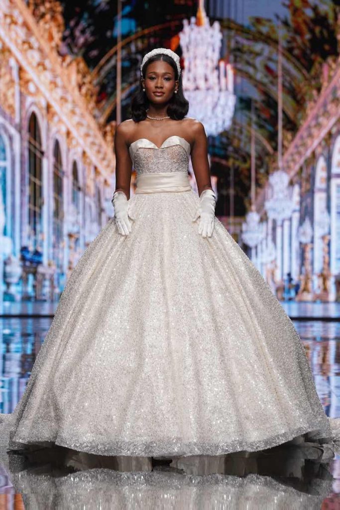 In questa foto una modella al Sì Sposaitalia Collezioni 2023 con un abito da sposa principessa dal tessuto glitterato di Amelia Casablanca