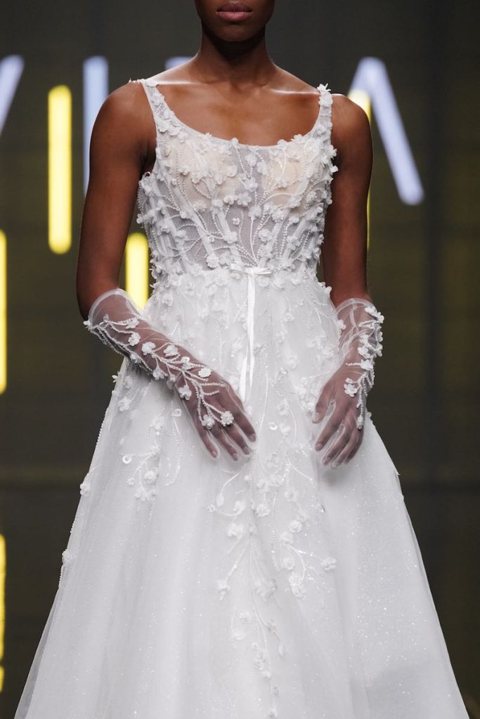In questa foto il dettaglio di una mdoella che indossa un abito da sposa della collezione Fiori di Dovita Bridal abbinato a guanti da sposa in tulle con micro fiori 3D