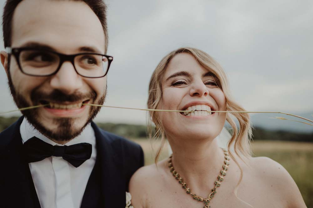 Una foto di Cristina e Riccardo del servizio di matrimonio realizzato da Paolo Mantovani, tra i fotografi di Torino: gli sposi sorridono tenendo tra i denti una spiga di grano