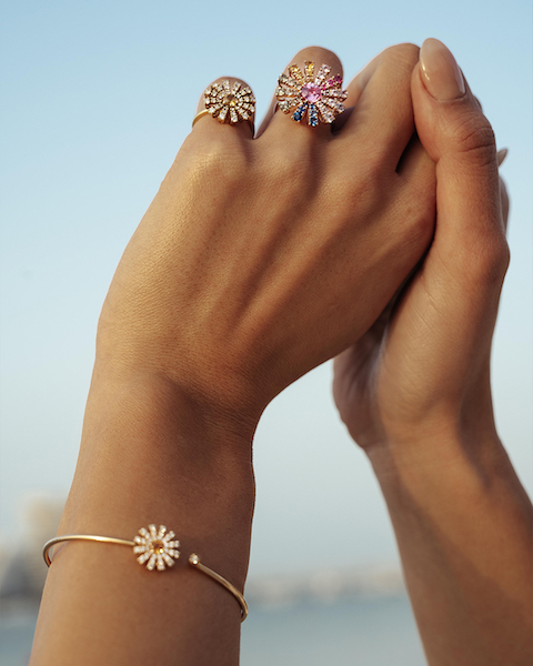 In questa foto le mani di una modella indossano due anelli multicolor, a forma di fiore, della collezione Damiani 2023