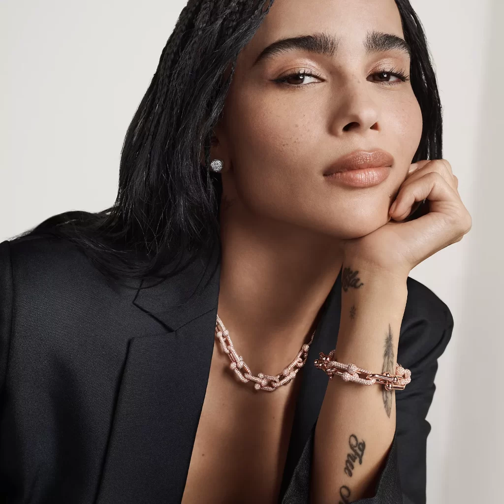 In questa foto Zoë Kravitz, testimonial Tiffany, posa con un collier e un bracciale a catena, in oro rosa.