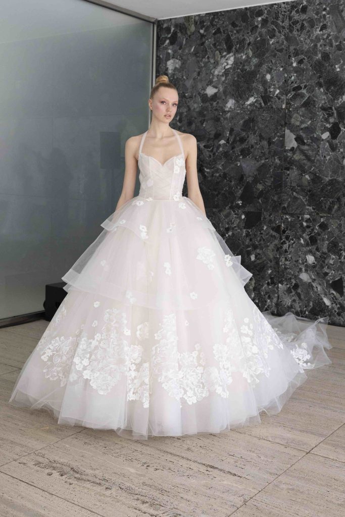 In questa immagine un abito da sposa ampio con decorazioni floreali.