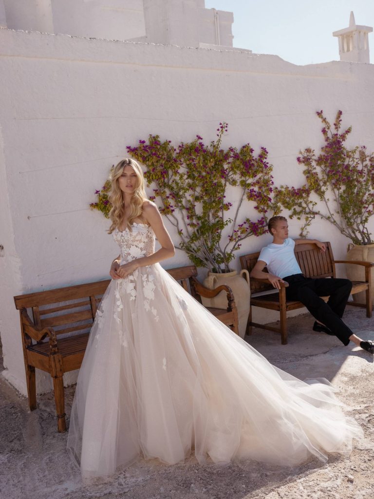 In questa immagine un abito da sposa  Adorious Collection by Modeca 2024 con pizzo floreale.