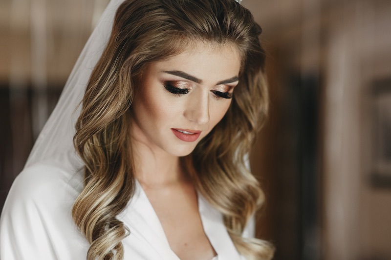 In questa foto una sposa con capelli mossi indossa un velo