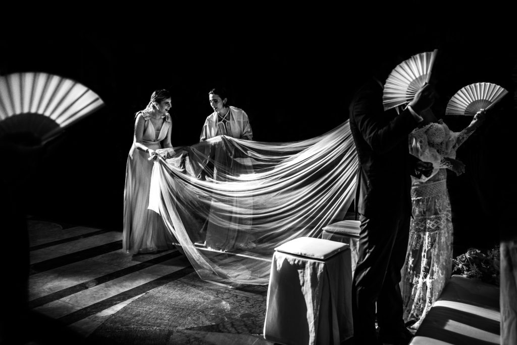 In questa foto in bianco e nero di Matteo Lomonte un gioco di luci coi ventagli e il velo creato dagli sposi Marilù e Jacopo e le damigelle