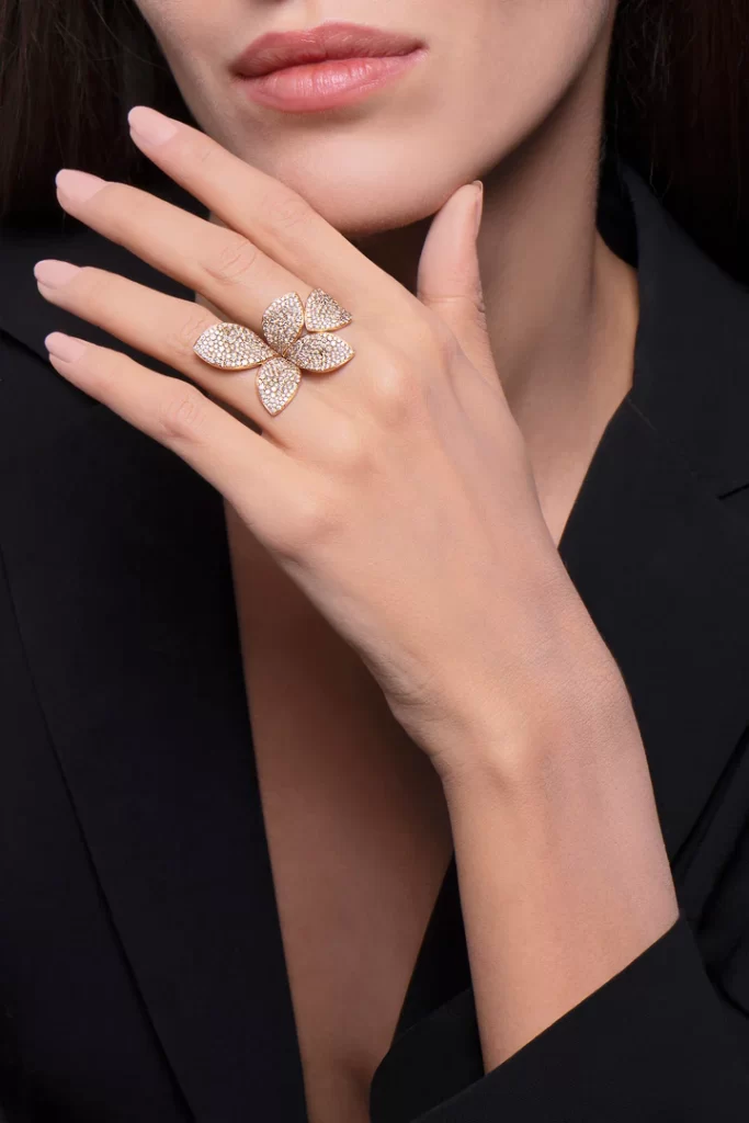 In questa foto le mani di una modella mostrano un anello in oro giallo e diamanti, a forma di fiore, della collezione di alata gioielleria Pasquale Bruni. I maxi anelli sono tra le grandi tendenze 2023 per i gioielli da donna