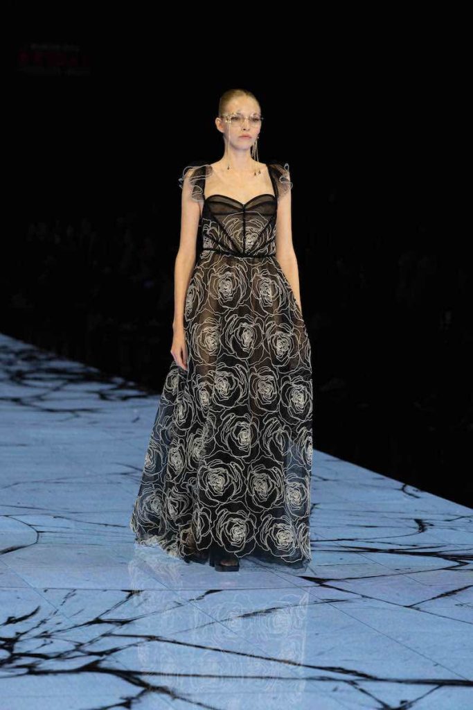In questa foto una modella sfila indossando un abito da sposa ad A di colore nero con ricami di rose bianche e corpetto a cuore 