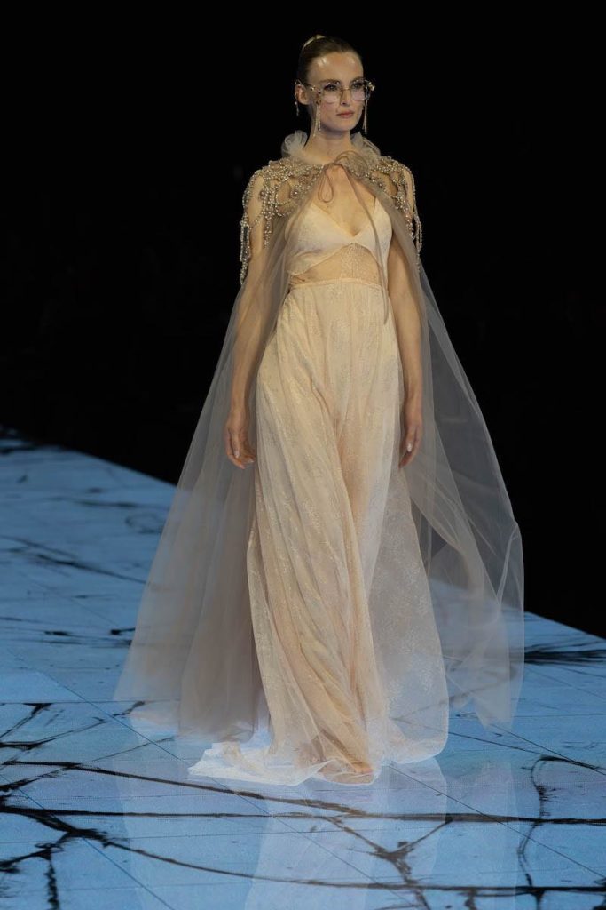 In questa foto una modella indossa un  abito da sposa scivolato color champagne con cappa abbinata