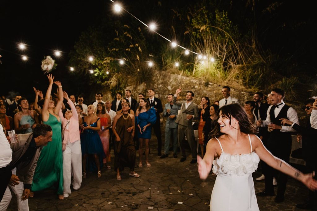 In questa immagine Laura Mencarelli lancia il bouquet indossando il secondo abito da sposa.