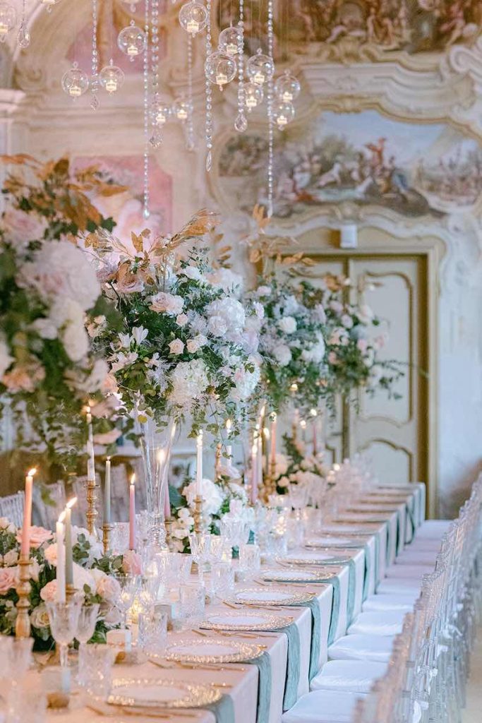 In questa foto un tavolo imperiale per matrimonio allestito da Giovanna Damonte con tovagliato, alzate di fiori e candele nei colori del rosa, del bianco e del verde salvia