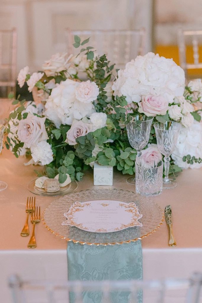 In questa foto il dettaglio di un matrimonio allestito da Giovanna Damonte con tovagliato, alzate di fiori e candele nei colori del rosa, del bianco e del verde salvia