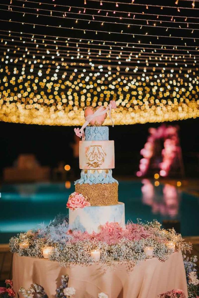 In questa foto una torta nuziale a piani nei toni del rosa, dell'azzurro e dell'oro