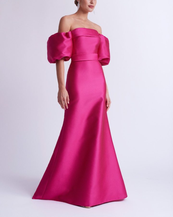 In questa foto una modella indossa un abito lungo di Rosa Clará in satin con maniche balloon rimovibili di colore fucsia per un look Barbiecore da cerimonia