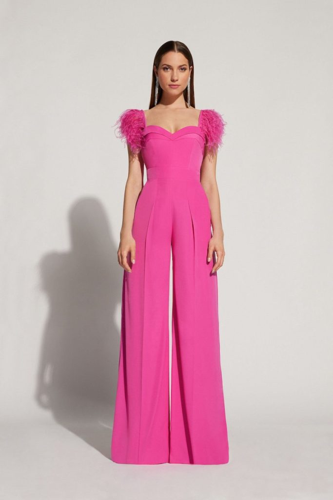 In questa foto una modella posa indossando una tuta elegante di Atelier Emé con plumage sulle spalle di colore rosa per un look Barbiecore da cerimonia