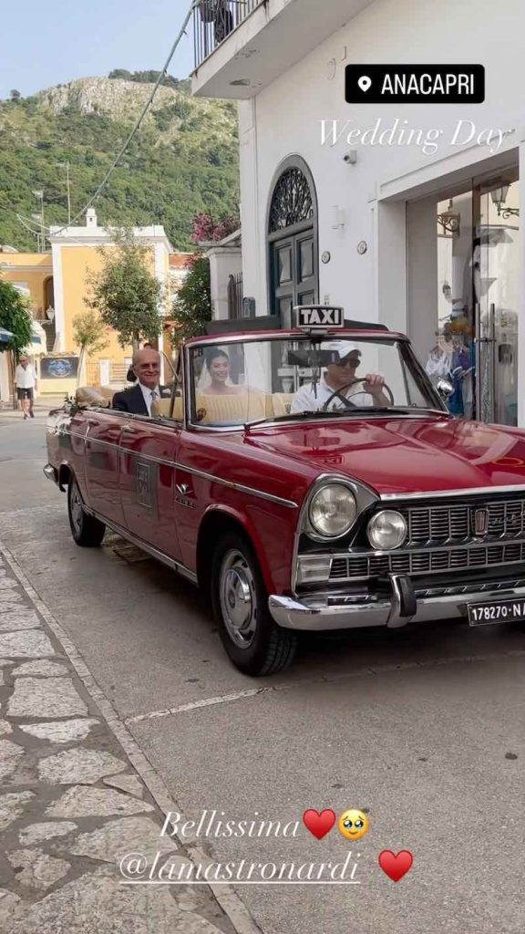 In questa foto un momento del matrimonio di Alessandra Mastronardi  a bordo di un taxi d'epoca di colore rosso in compagnia del papà