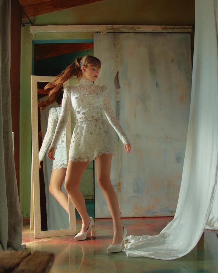 In questa foto Annalisa danza in abito da sposa corto Dolce&Gabbana in pizzo e perline. Il modello presenta collo alto e maniche lunghe. La cantante indossa anche un paio di décolleté