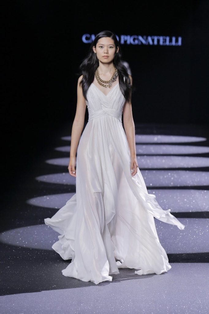In questa foto una modella sfila indossando un abito da sposa di Carlo Pignatelli modello scivolato in chiffon