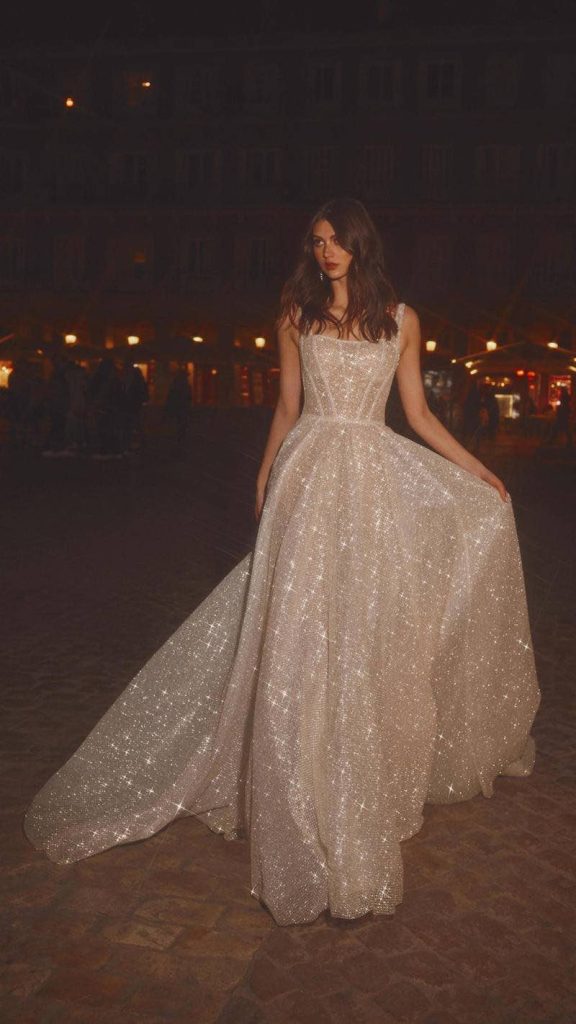 In questa foto una modella posa indossando un abito da sposa ad A con tessuto sparkling di Galia Lahav