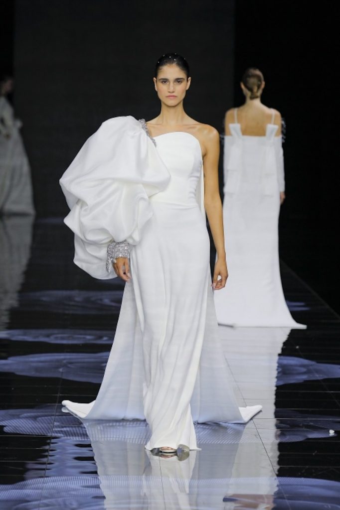 In questa foto una modella sfila indossando un abito da sposa scivolato in georgette con spallina oversize sulla manica destra
