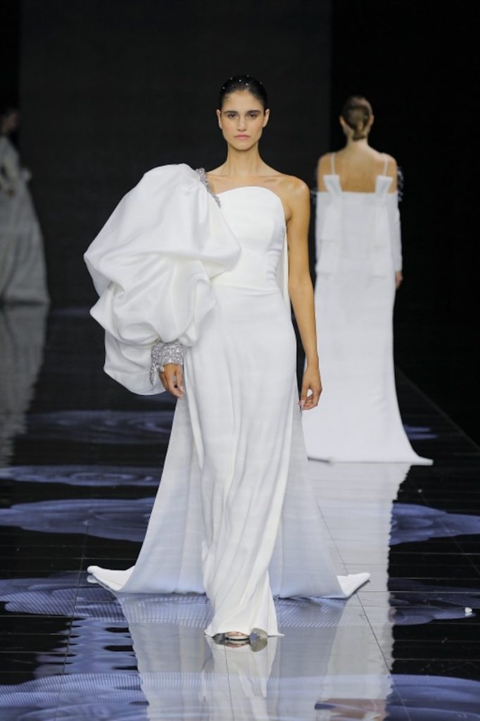 In questa foto una modella sfila indossando un abito da sposa scivolato in georgette con spallina oversize sulla manica destra