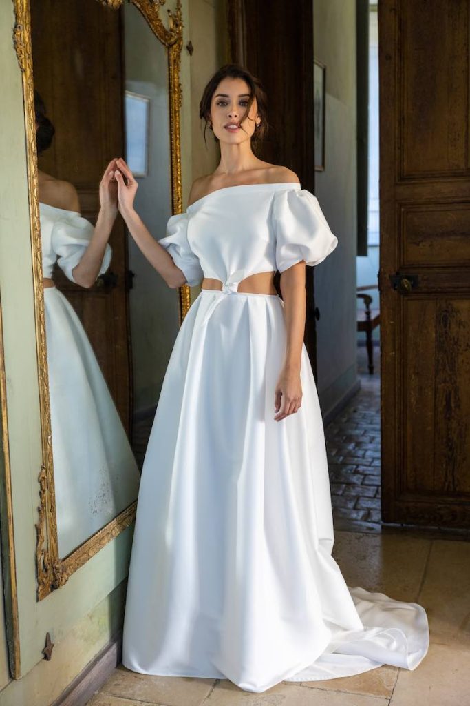 In questa foto una modella posa indossando un abito da sposa ad A con maniche balloon ed effetto cut out sul busto di Cymbeline