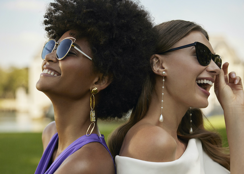 In questa foto una sposa posa schiena a schiena con la sua amica. Si tratta di un'immagine di campagna del brand di abiti da sposa Rosa Clarà