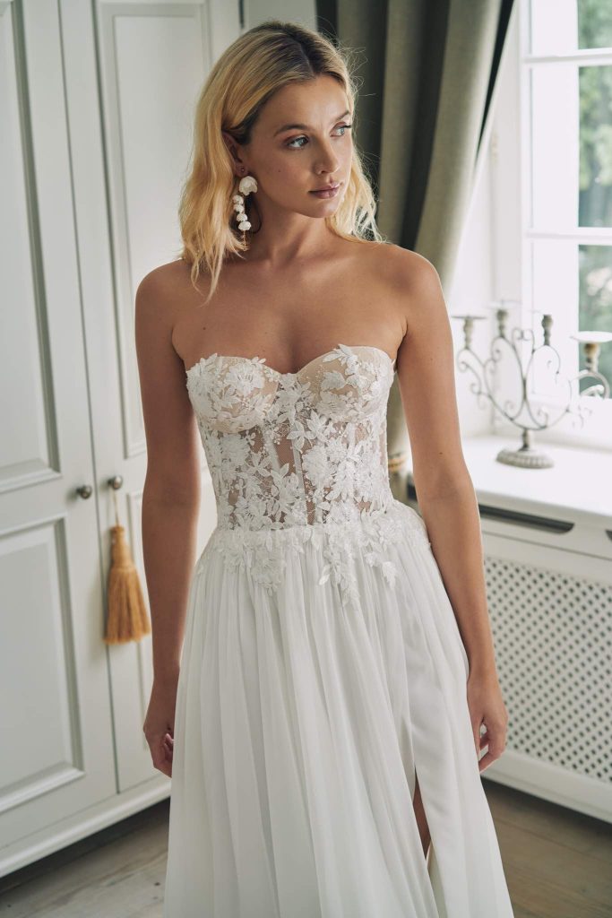 In questa immagine un abito da sposa con corpetto interamente ricamato in pizzo con decori floreali. 