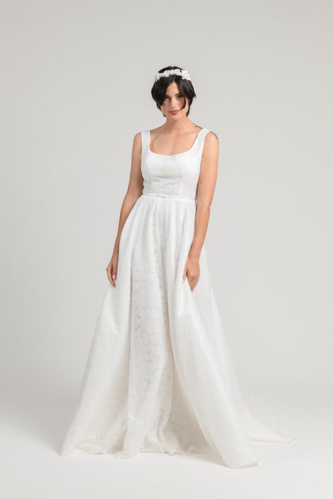 In questa foto una modella posa indossando un abito da sposa scivolato con scollo quadrato e micro fiocco in vita dell'Atelier Benedetta di Palermo