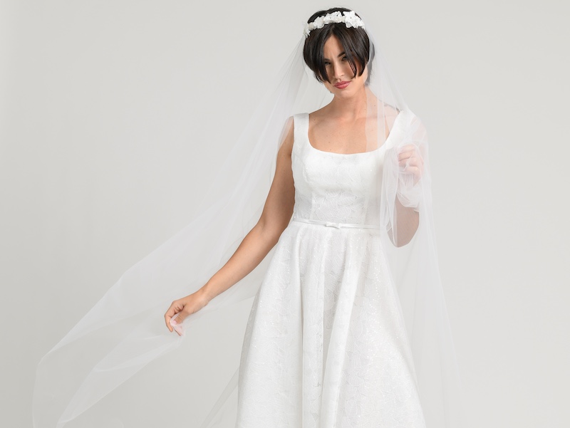 In questa una modella posa indossando un abito da sposa ad A con scollo quadrato della collezione Unique di Atelier Benedetta