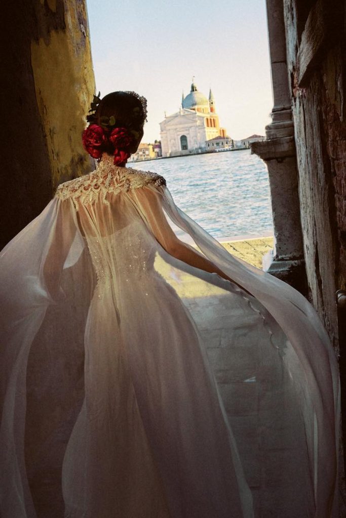 In questa foto una modella corre di spalle a Venezia indossando un abito da sposa Maison Signore