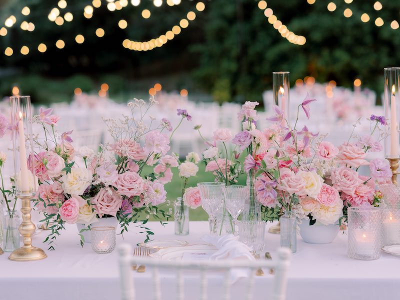 In questa foto un dettaglio della mise en place del matrimonio di Gabriele e Cecilia realizzata con composizione di fiori di colore rosa, lilla e bianco, piatti e posate di colore oro e piccoli portacandele in vetro