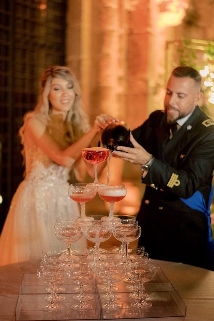 In questa foto due sposi versano lo Champagne Rosé su una Champagne Tower
