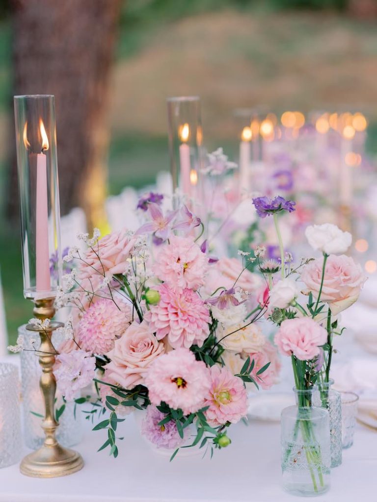 In questa foto un dettaglio della mise en place del matrimonio di Gabriele e Cecilia realizzata con composizione di fiori di colore rosa, lilla e bianco, piatti e posate di colore oro e piccoli portacandele in vetro e candelabri di colore oro