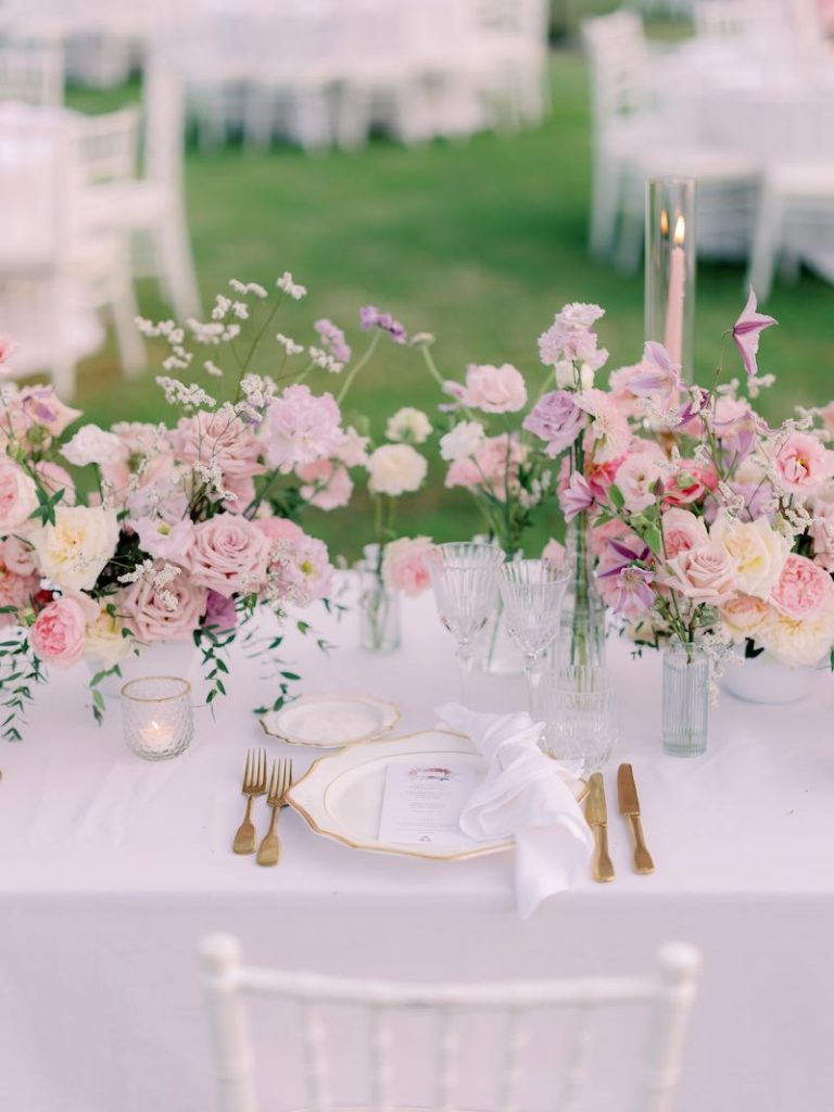 In questa foto un dettaglio della mise en place del matrimonio di Gabriele e Cecilia realizzata con composizione di fiori di colore rosa, lilla e bianco, piatti e posate di colore oro e piccoli portacandele in vetro
