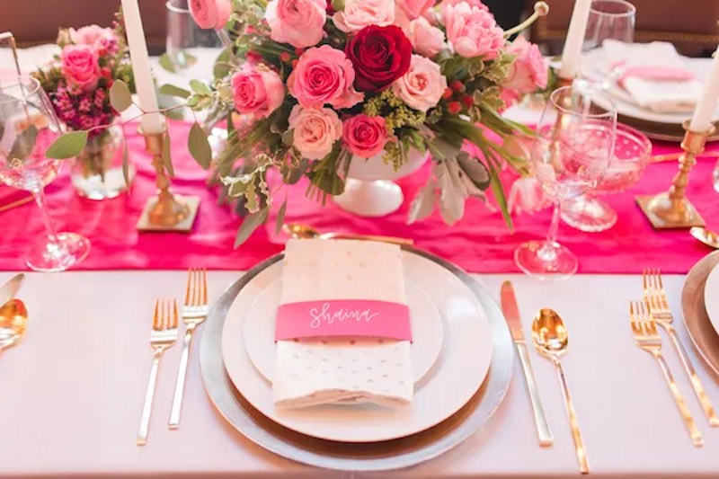 In questa foto il dettaglio di una mise en place per matrimonio stile Barbie con runner e segnaposto di colore fucsia e decorazioni di fiori di colore rosa e fucsia